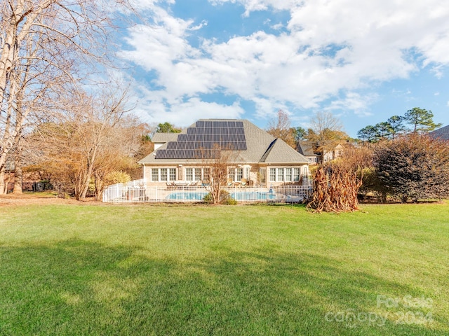 back of house featuring solar panels and a lawn