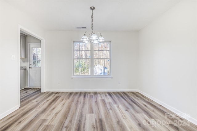 unfurnished dining area with a wealth of natural light, light hardwood / wood-style floors, and a notable chandelier