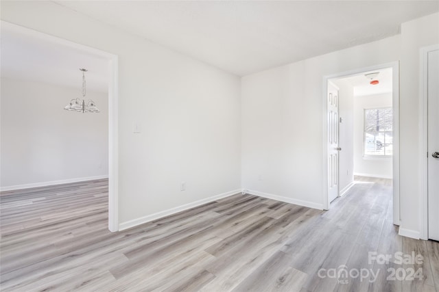 spare room with light hardwood / wood-style floors and a chandelier