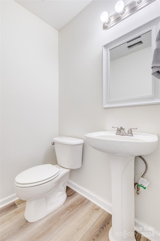 bathroom featuring a textured ceiling, hardwood / wood-style flooring, toilet, and sink