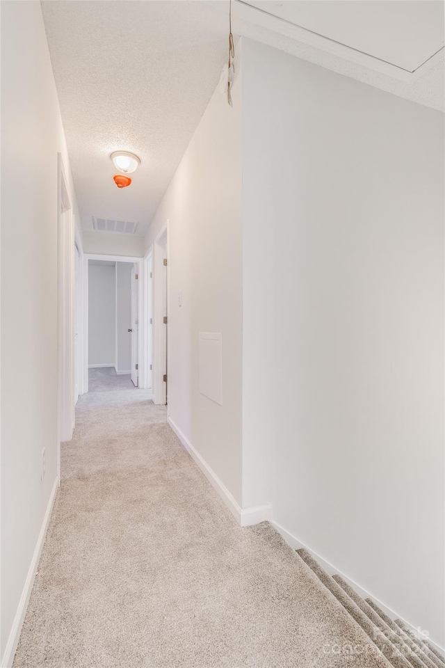 hall with light carpet and a textured ceiling