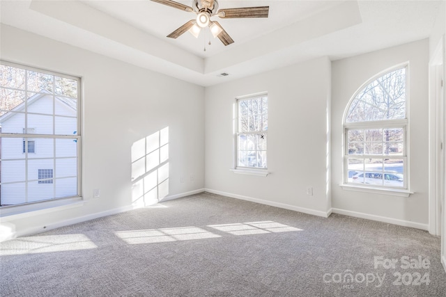 carpeted empty room featuring a raised ceiling and ceiling fan