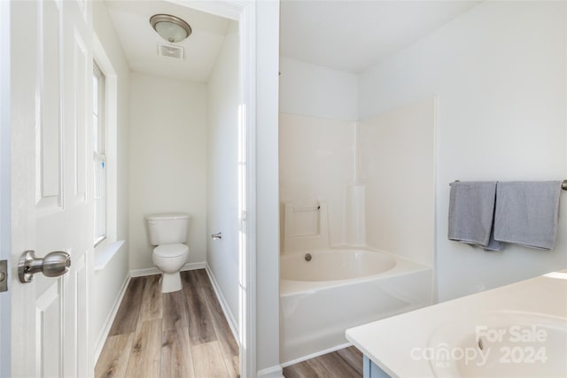 full bathroom featuring hardwood / wood-style floors, vanity, shower / bath combination, and toilet