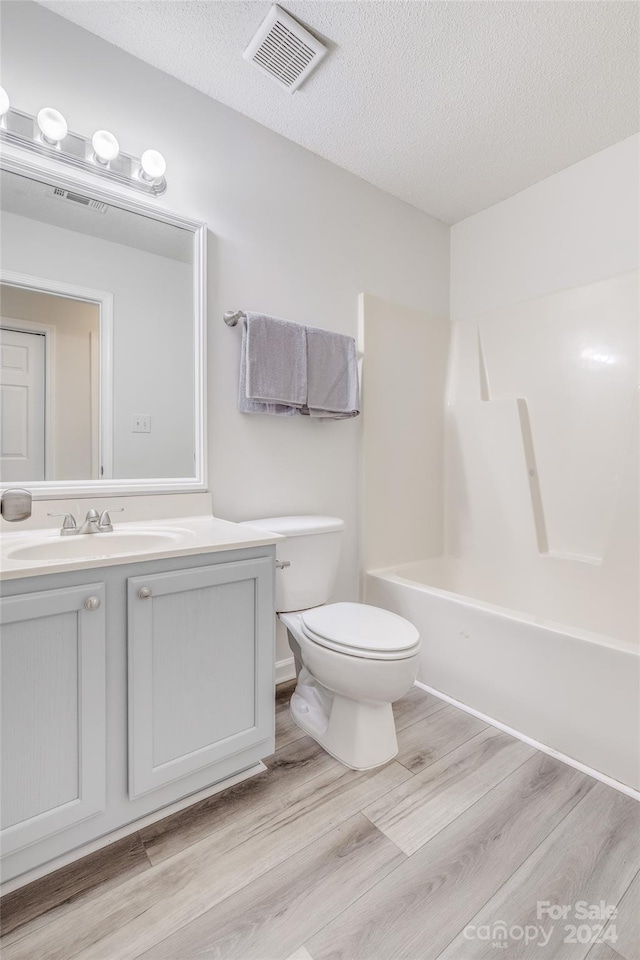 full bathroom with bathtub / shower combination, hardwood / wood-style floors, a textured ceiling, and vanity