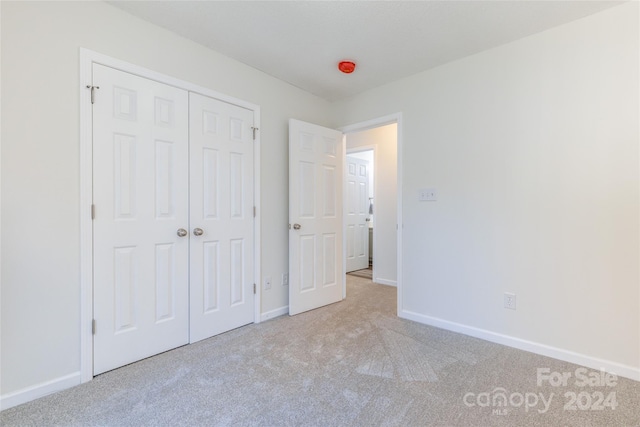 unfurnished bedroom with light carpet and a closet