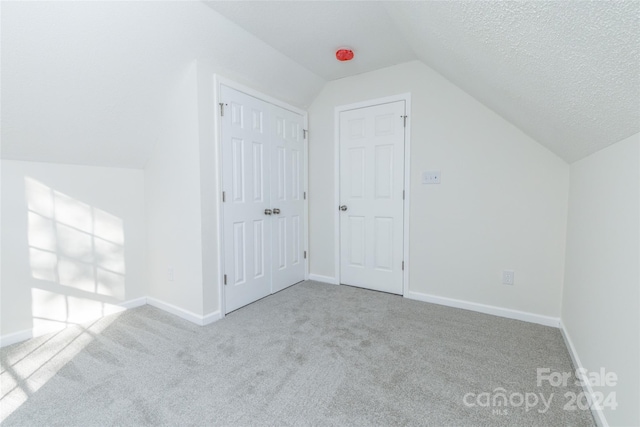 bonus room featuring a textured ceiling, light colored carpet, and vaulted ceiling