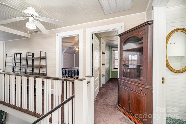 hall featuring wooden walls and dark colored carpet