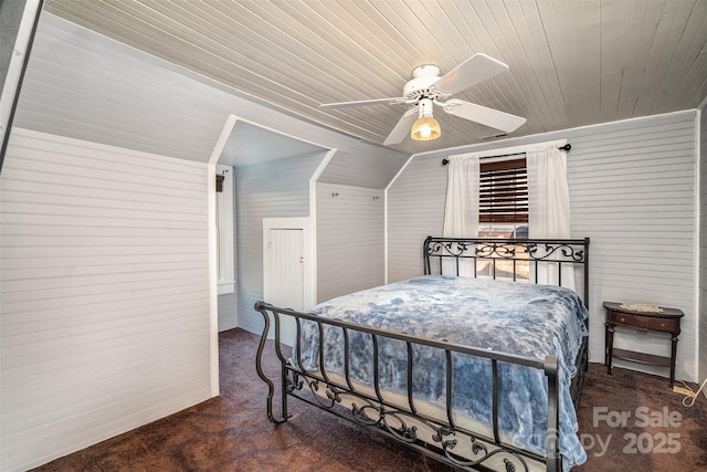 bedroom with ceiling fan, lofted ceiling, dark colored carpet, and wooden walls