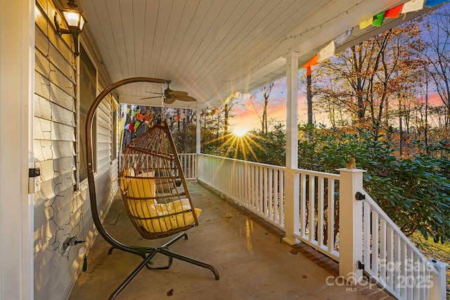 balcony at dusk featuring a porch and ceiling fan