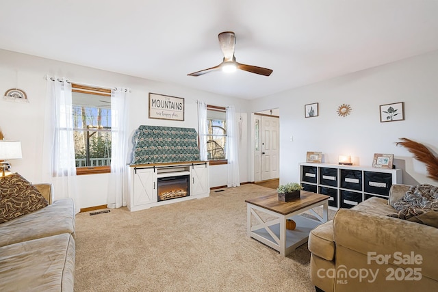 living room featuring carpet flooring, a fireplace, ceiling fan, and a wealth of natural light