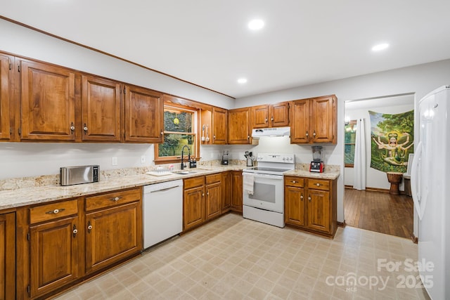 kitchen with white appliances, a healthy amount of sunlight, light stone countertops, and sink