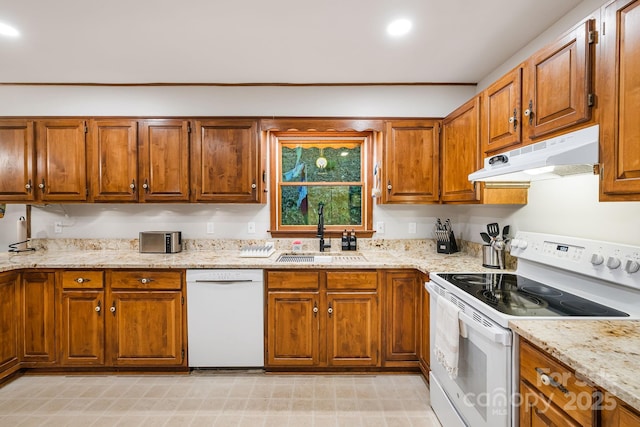 kitchen with white appliances, light stone counters, and sink