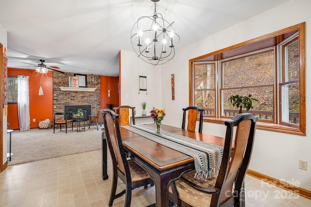 carpeted dining room featuring ceiling fan with notable chandelier and a brick fireplace