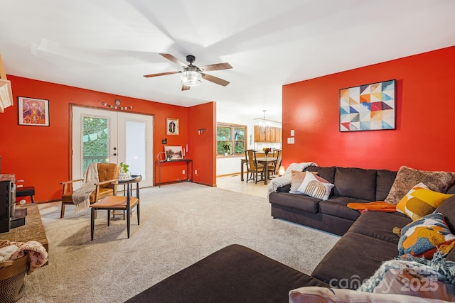 carpeted living room featuring ceiling fan with notable chandelier and french doors