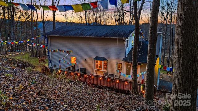 back house at dusk featuring a wooden deck