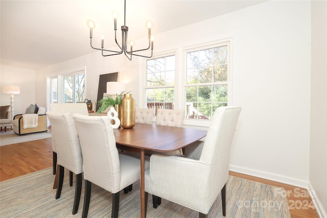 dining space with hardwood / wood-style floors, a healthy amount of sunlight, and a chandelier