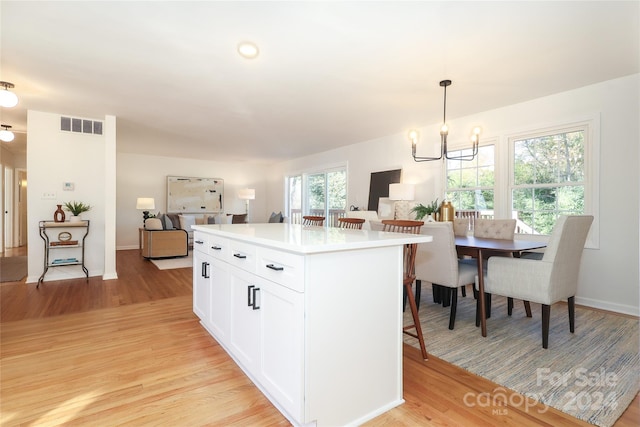 kitchen featuring decorative light fixtures, light hardwood / wood-style flooring, a notable chandelier, white cabinets, and a center island