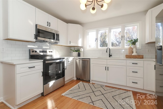 kitchen with sink, white cabinets, light wood-type flooring, and appliances with stainless steel finishes