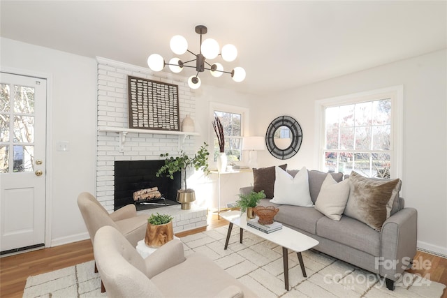 living room with a chandelier, wood-type flooring, and a brick fireplace