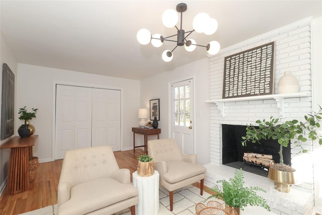 living room featuring light hardwood / wood-style flooring, a chandelier, and a brick fireplace