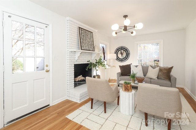 living room with a notable chandelier, a fireplace, and light hardwood / wood-style flooring