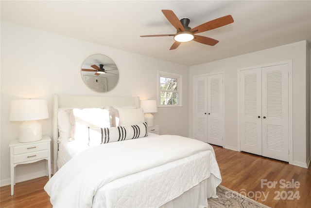 bedroom featuring ceiling fan, multiple closets, and light hardwood / wood-style flooring