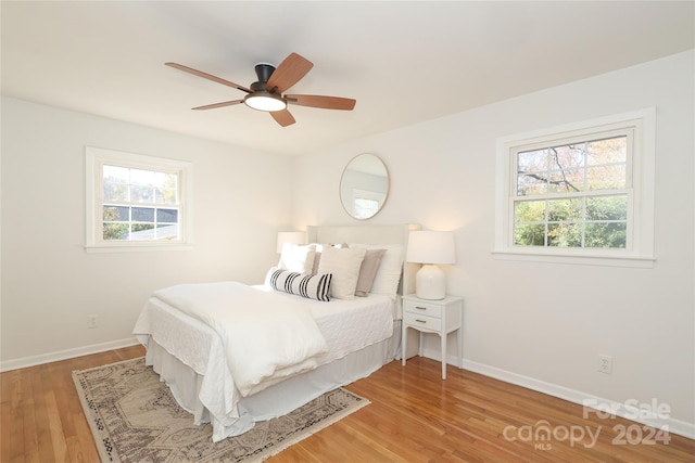 bedroom with multiple windows, ceiling fan, and hardwood / wood-style floors