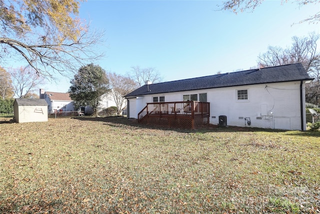 back of house with central AC unit, a storage unit, a lawn, and a wooden deck