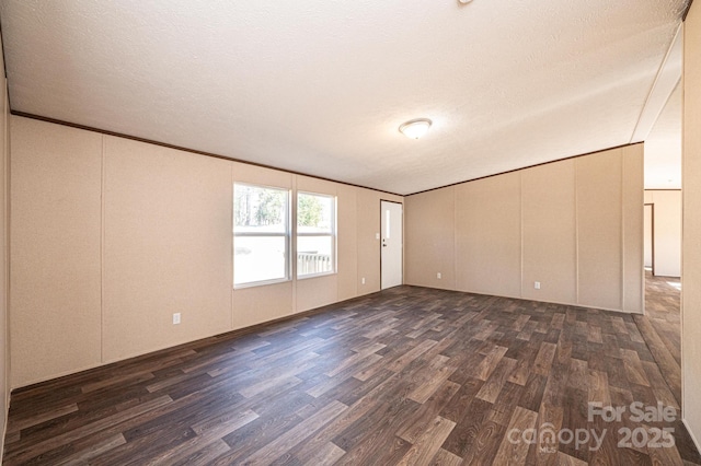 empty room featuring ornamental molding, dark hardwood / wood-style floors, and a textured ceiling