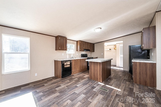 kitchen featuring lofted ceiling, dark hardwood / wood-style flooring, a center island, black appliances, and a textured ceiling