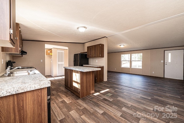 kitchen featuring a breakfast bar area, black fridge, a textured ceiling, dark hardwood / wood-style flooring, and a kitchen island