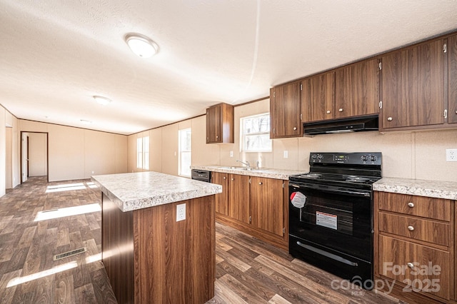 kitchen with sink, dark wood-type flooring, a center island, black appliances, and a textured ceiling