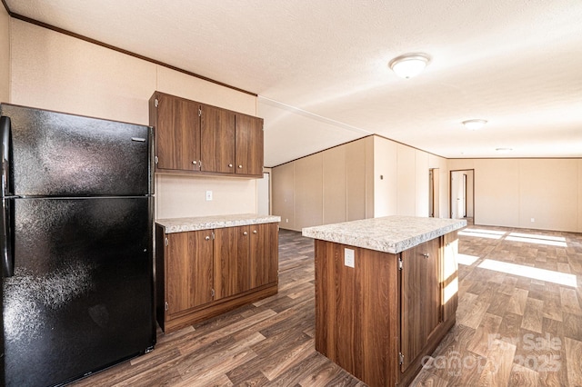 kitchen featuring black fridge, dark hardwood / wood-style floors, a kitchen island, and crown molding