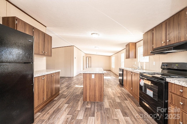 kitchen with a kitchen island, sink, dark hardwood / wood-style flooring, black appliances, and crown molding