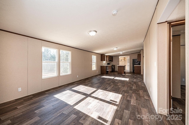 unfurnished living room with crown molding, dark hardwood / wood-style floors, and vaulted ceiling