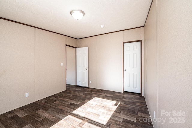 spare room featuring ornamental molding, dark hardwood / wood-style floors, and a textured ceiling