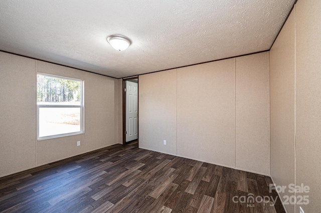 empty room with crown molding, dark hardwood / wood-style floors, and a textured ceiling