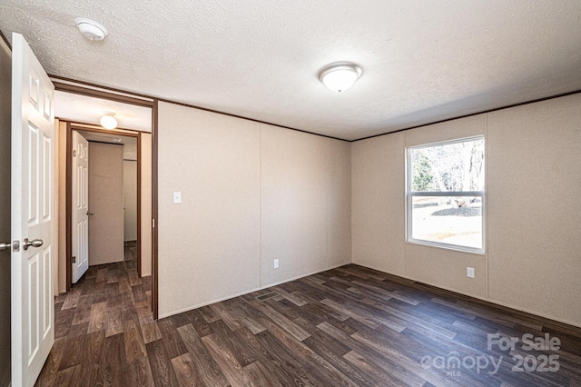 spare room featuring crown molding, a textured ceiling, and dark hardwood / wood-style flooring