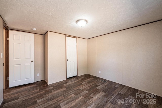 unfurnished bedroom with dark wood-type flooring, ornamental molding, a closet, and a textured ceiling