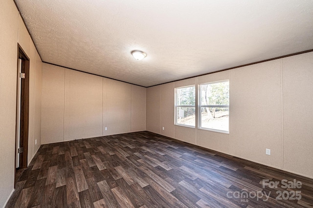 empty room with ornamental molding, dark hardwood / wood-style floors, and a textured ceiling