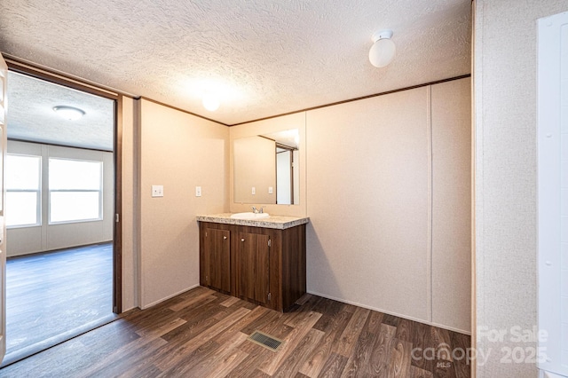 bathroom featuring crown molding, wood-type flooring, vanity, and a textured ceiling