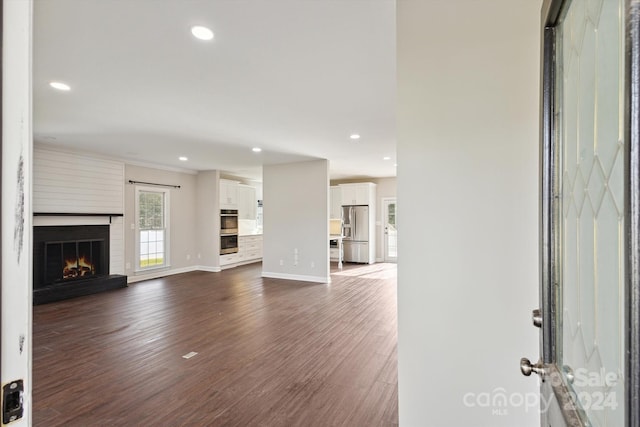 unfurnished living room featuring a large fireplace, dark hardwood / wood-style flooring, and crown molding