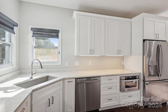 kitchen with appliances with stainless steel finishes, white cabinetry, and sink