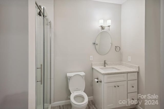 bathroom with toilet, vanity, wood-type flooring, and walk in shower