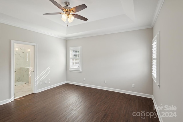 empty room with dark hardwood / wood-style floors, a raised ceiling, ceiling fan, and ornamental molding