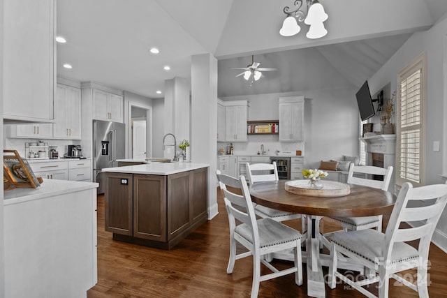 dining area with ceiling fan with notable chandelier, sink, vaulted ceiling, dark hardwood / wood-style flooring, and beverage cooler