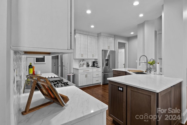 kitchen featuring sink, light stone countertops, high quality fridge, dark hardwood / wood-style flooring, and white cabinetry