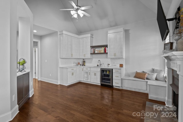 interior space with sink, dark wood-type flooring, beverage cooler, vaulted ceiling, and white cabinets