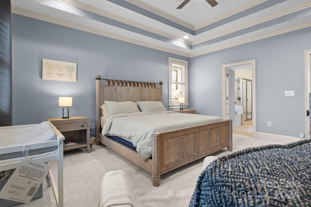 bedroom featuring ensuite bathroom, ceiling fan, ornamental molding, a tray ceiling, and light colored carpet