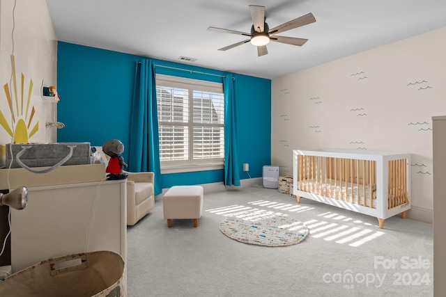 carpeted bedroom with a nursery area and ceiling fan